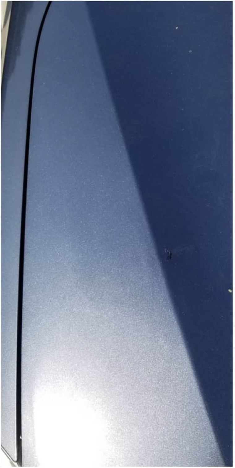 The same blue quarter panel after paintless dent repair, flawless