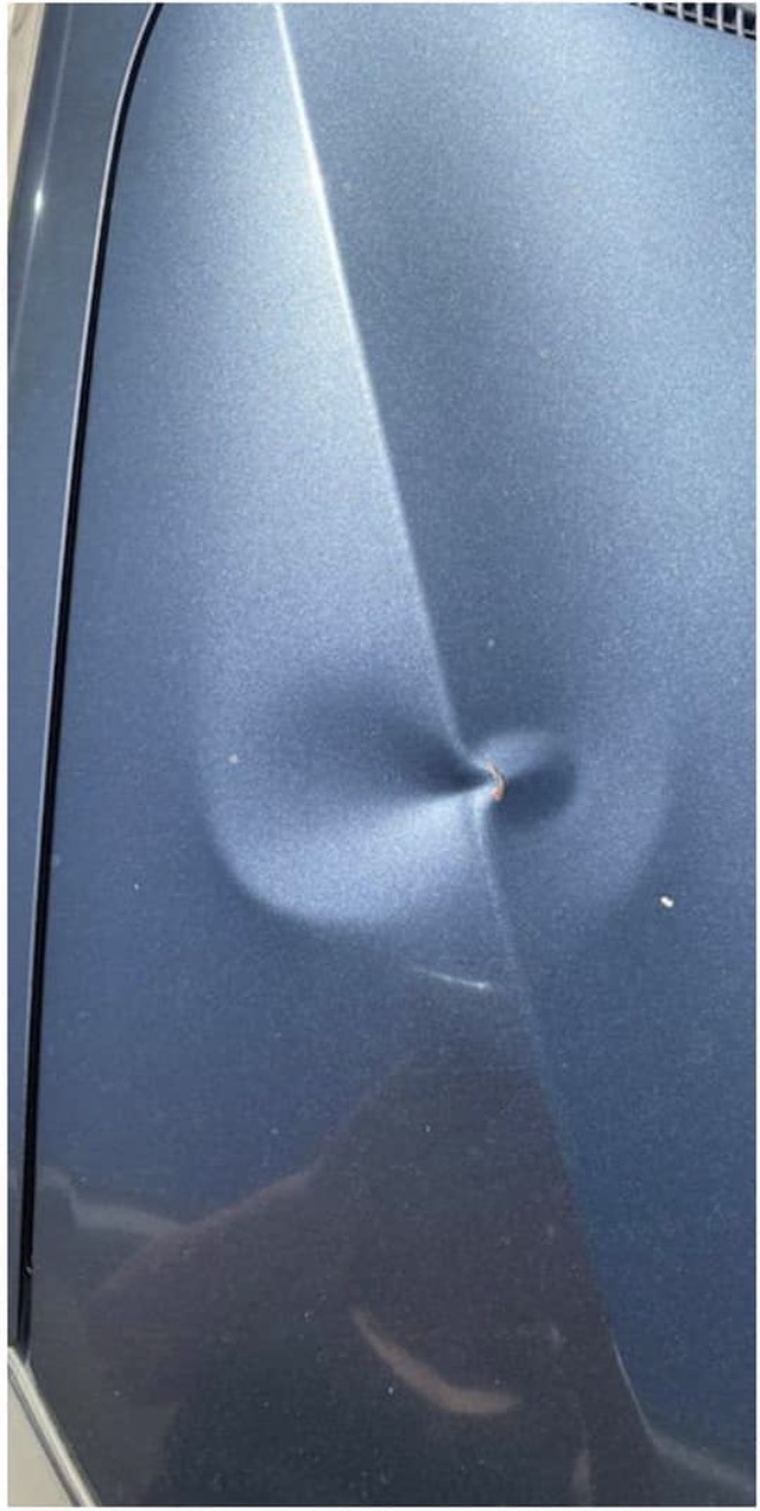 Sharp dent and crease in a blue quarter panel before repair